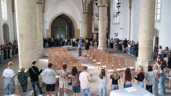 Auf dem Foto sieht man den Innenraum der Christuskirche, wo Familien mit dem Jugendlichen um die Stuhlreihen einen großen Kreis gebildet haben.