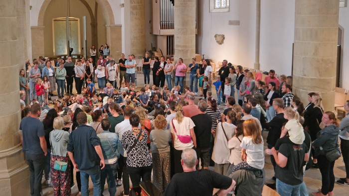 Auf dem Foto sieht man den Innenraum der Christuskirche, wo Familien mit dem Jugendlichen um die Stuhlreihen einen großen Kreis gebildet haben.