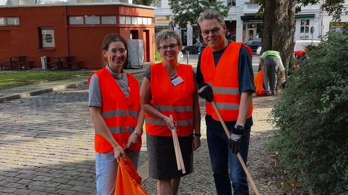 Vikarin Franziska Zellmer, Pfarrerin Martina Steffen-Elis und Bezirksbürgermeister Jörn Oltmann mit Besen, Müllzange und Müllbeutel