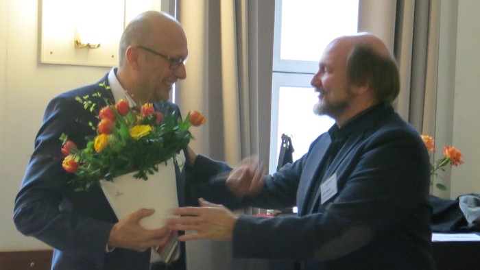 Zwei Männer tauschen einen Blumenstrauß aus.