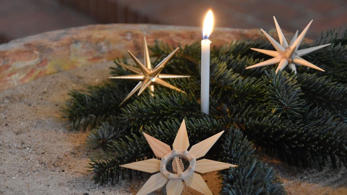 Weihnachtliche Deko mit Kerze und Holzsterne auf Steinplatte