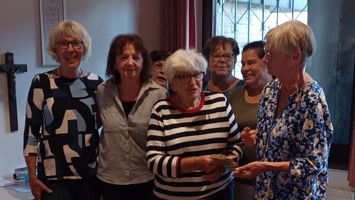 Ein Gruppe von Frauen steht um einen Tisch mit Kuchen.