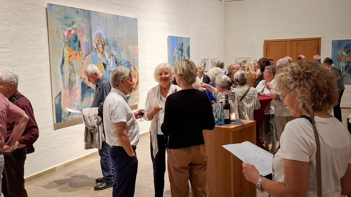Eine Gruppe Menschen im Gespräch bei einer Ausstellungseröffnung