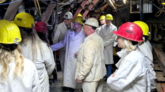 Eine Gruppe von Menschen in Schutzanzügen und Helmen steht in einem zerstörten Gebäude.