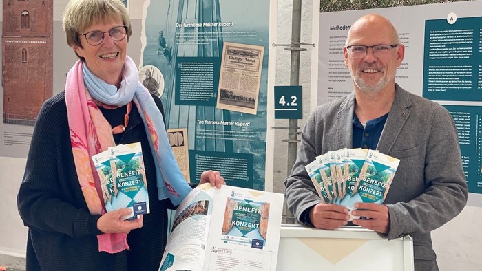 Zwei Personen präsentieren Bücher und Informationsmaterialien an einem Stand