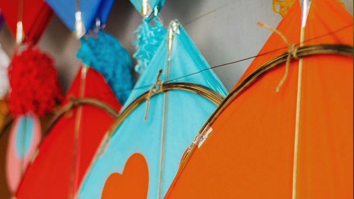 Bunte Drachen hängen an Wand.