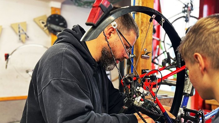 Erwachsener und Jugendlicher reparieren ein Fahrrad.
