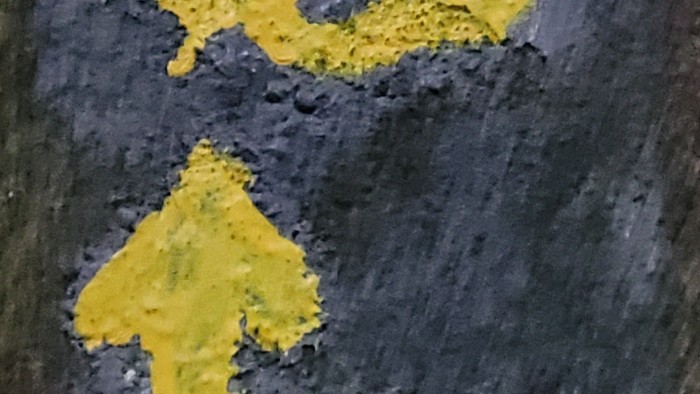 Das Bild zeigt zwei gelbe Symbole auf schwarzem Hintergrund