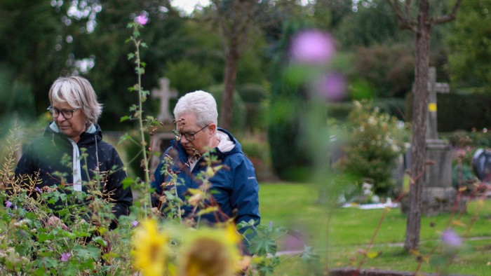 Zwei Frauen hinter einem Wildblumenbeet auf einem Friedhof