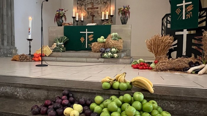 Buntes Obstarrangement vor Kirchenaltar mit Kerzen und Kreuz