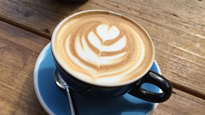 Eine Tasse Kaffee mit Milchschaumherz auf einem Holztisch