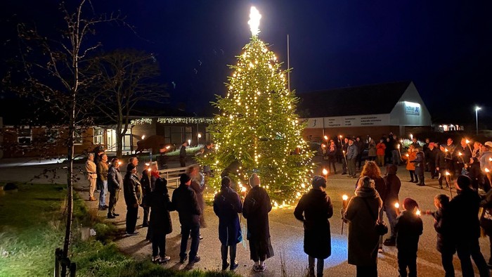 En juletræ fest med folk med lysekøn og lysede træer