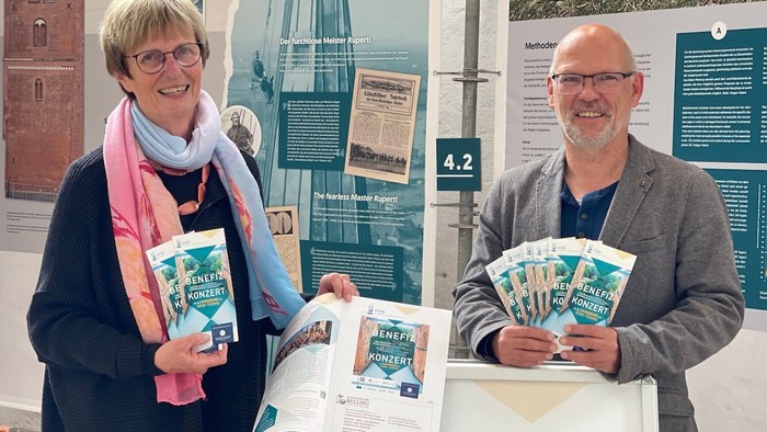 Zwei Personen präsentieren Bücher und Informationsmaterialien an einem Stand