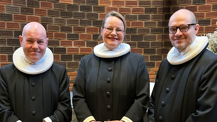 Tre præster står sammen i kirke.