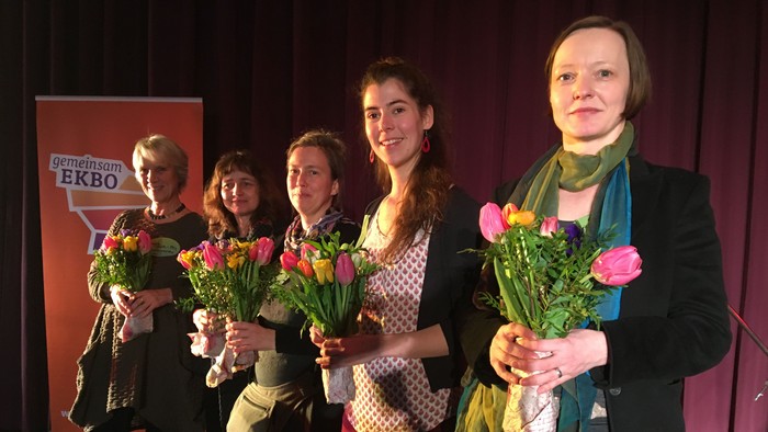 Fünf Frauen halten Blumensträuße und lächeln