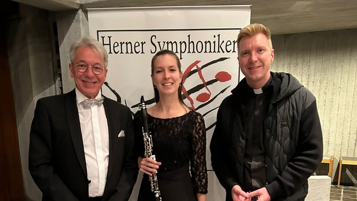 Drei Personen vor einem Plakat der Herener Symphoniker