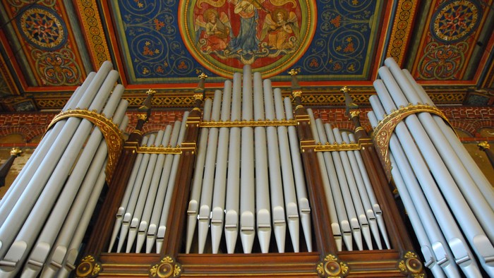 Prächtige Kirchenorgel vor farbenfroher Deckenmalerei