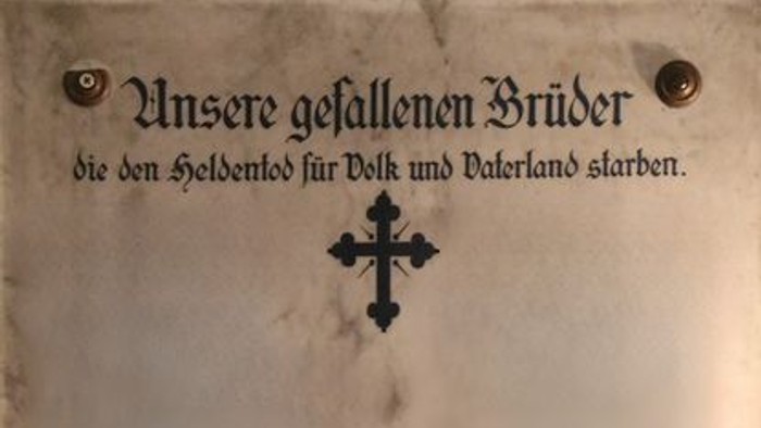 Gedenktafel mit Kreuz und Inschrift in deutscher Sprache