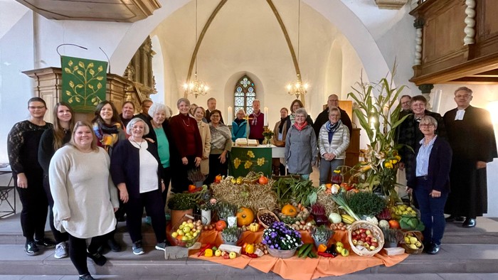 Gruppe von Menschen vor einem Erntedankaltar in einer Kirche