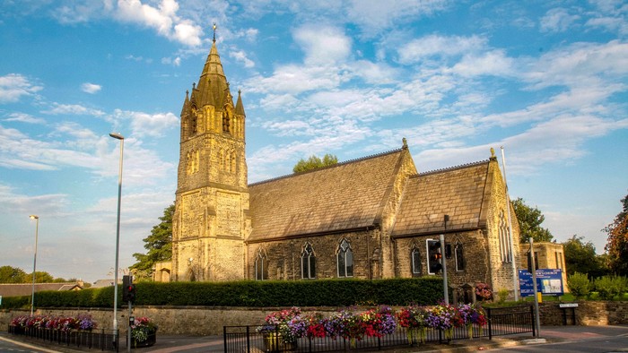 Church with tall tower and colorful flowers in front