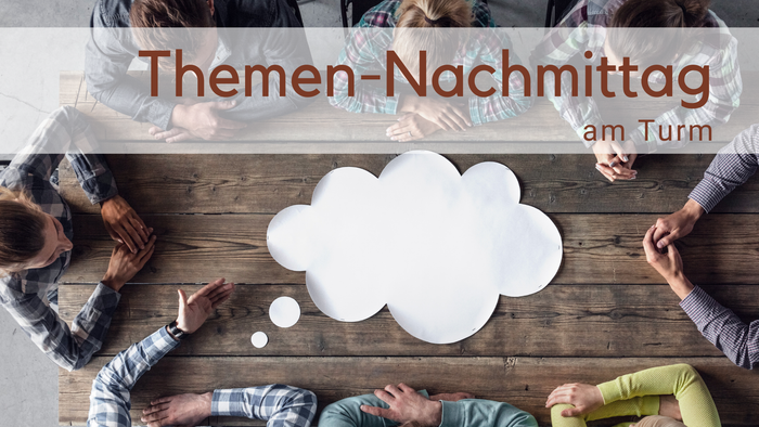 Menschen um einen Tisch von oben fotografiert. In der Mitte eine weiße Gedankenblase