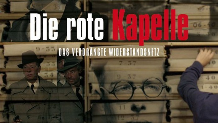 Der Filmplakat zeigt eine Wand mit alten Fotos und eine Hand, die nach einem Bild greift.