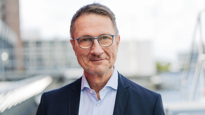 Mann mit Brille in businesskleidung vor moderner Stadtlandschaft