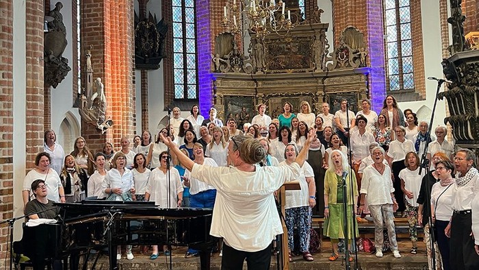 Chorsänger:innen vor dem Altar mit Dirigentin und begleitet am Flügel