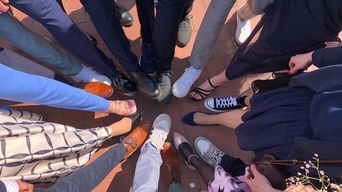 Menschen, die im Kreis stehen und ihre Füße und Schuhe zeigen.