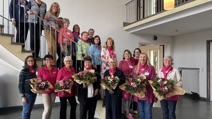 Ein Gruppe von Frauen feiert gemeinsam, einige halten Blumensträuße