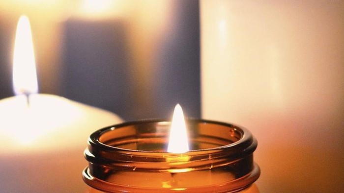 Zwei brennende Kerzen in Glasgefäßen auf einem Tisch