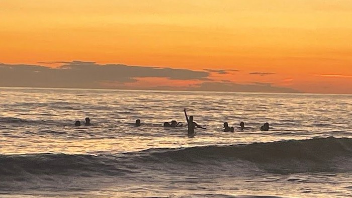 Surfer bei Sonnenuntergang am Meer