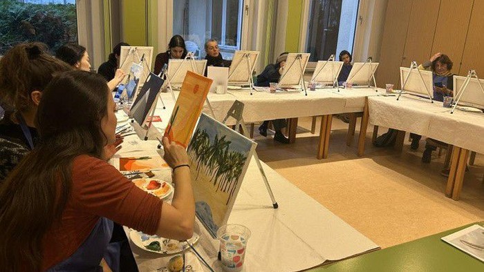 Künstler malen in einem hellen Raum an verschiedenen Staffeleien