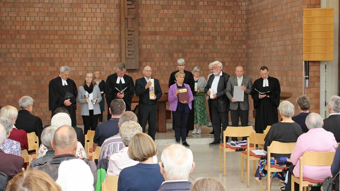 Mitglieder des Presbyteriums der Kirchengemeinde tragen besondere liturgische Gegenstände, wie die Altarbibel, das Abendmahlsgeschirr und die Osterkerze, aus dem Martin-Luther-Zentrum heraus. Foto: EKP/Oliver Claes