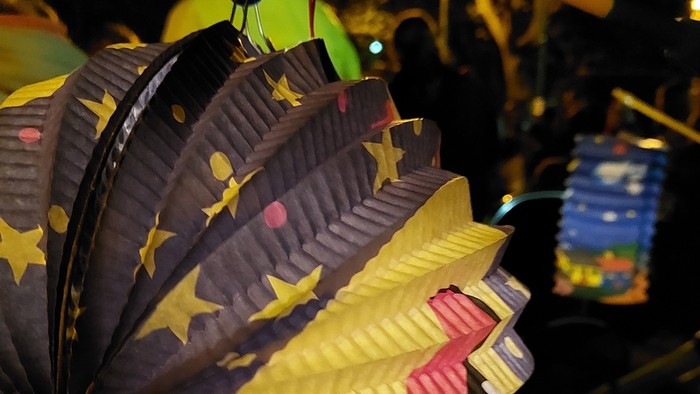 Bunte Laterne mit Sternen und Farben hängt an Holzstange