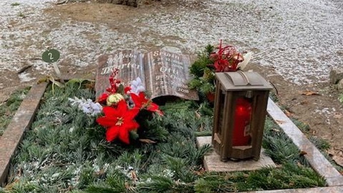 Ein Grabmal mit Weihnachtsdekoration und Laterne im Wald