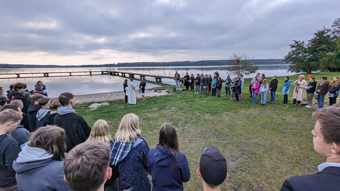 Jugendliche feiern beim Konficamp einen Taufgottesdienst am See.