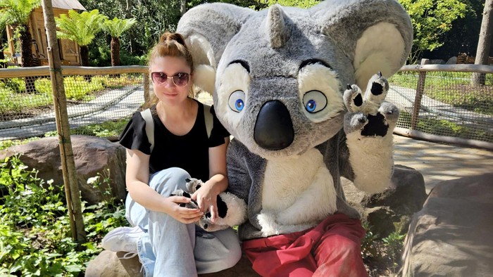 Ein Mädchen posiert mit einem Koala-Maskottchen im Zoo.