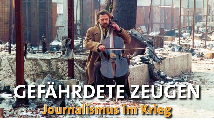 Mann sitzt auf einer Mauer und spielt ein Instrument. Im Hintergrund zerstörtes Gelände.