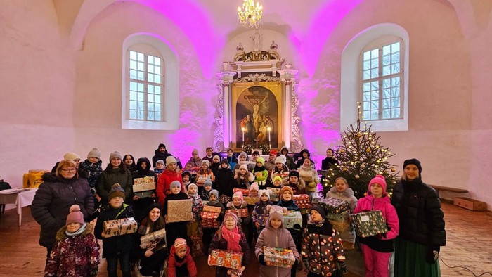 Gruppe von Menschen in Kirche mit Weihnachtsbäumen und Geschenken