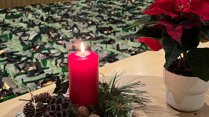 En juledekoreret bord med lysende lygte, grønne planter og pynt.