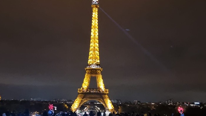 Beleuchteter Eiffelturm bei Nacht mit einem Lichtstrahl