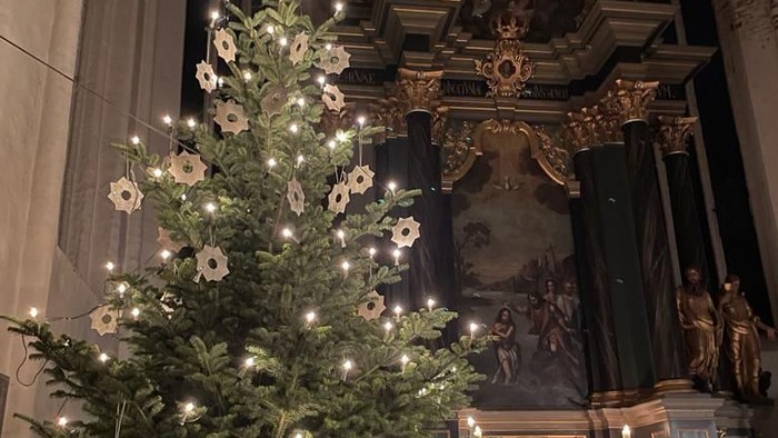 Weihnachtsbaum in der Kirche mit Lichtern und weißen Blumen