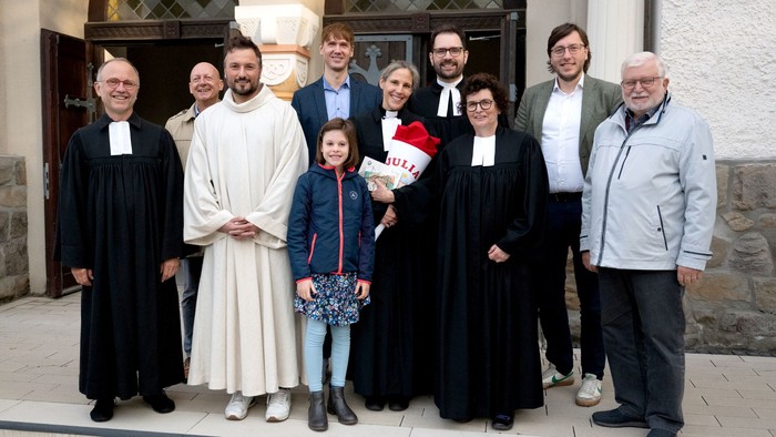 Eine Gruppe von Menschen posiert vor einer Kirche, darunter Priester und Familienmitglieder.
