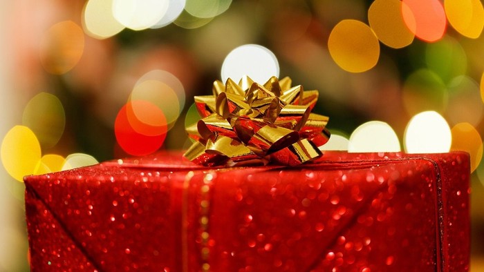 Et rødt og glitrende julepakke med en rød og guld farvet bue på.