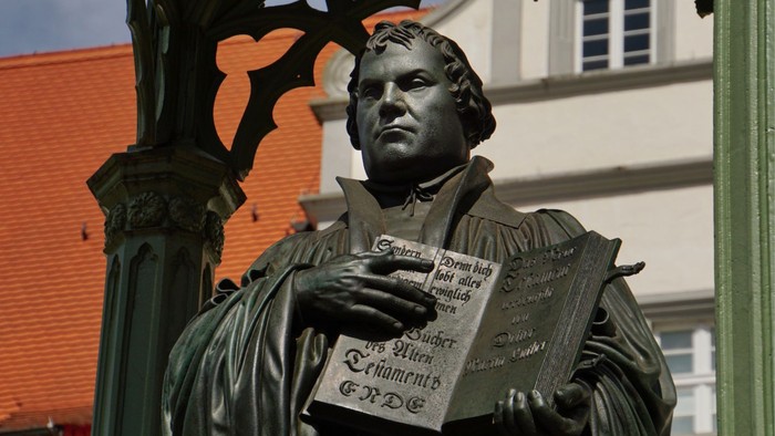 Lutherdenkmal (Ausschnitt) vor rotem Dach und heller Hausfassade