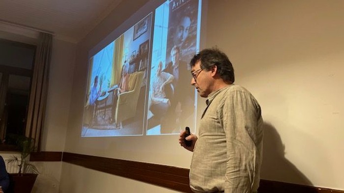 Mand ved projektor med billeder af mænd og møbler.