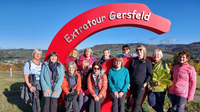 Eine Gruppe von Wanderern posiert vor dem Extratour Gersfeld Schild
