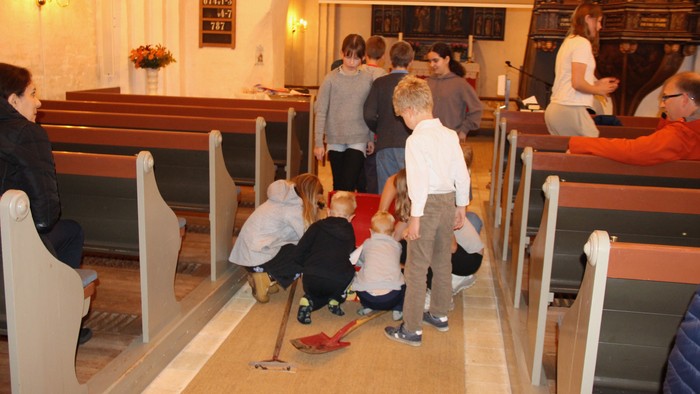 Børn samles om en skattekiste på kirke gangen.Der ligger både spade og skuffejern på gulvet også.