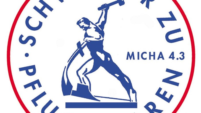 Das Bild zeigt ein kreisförmiges Logo mit einer blauen Figur, die einen Hammer hebt, umgeben von deutschem Text und dem Verweis *„MICHA 4.3“*.